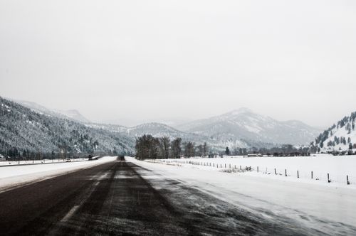 Free Discover a serene winter road scene with snow-covered mountains under a gray sky. Stock Photo