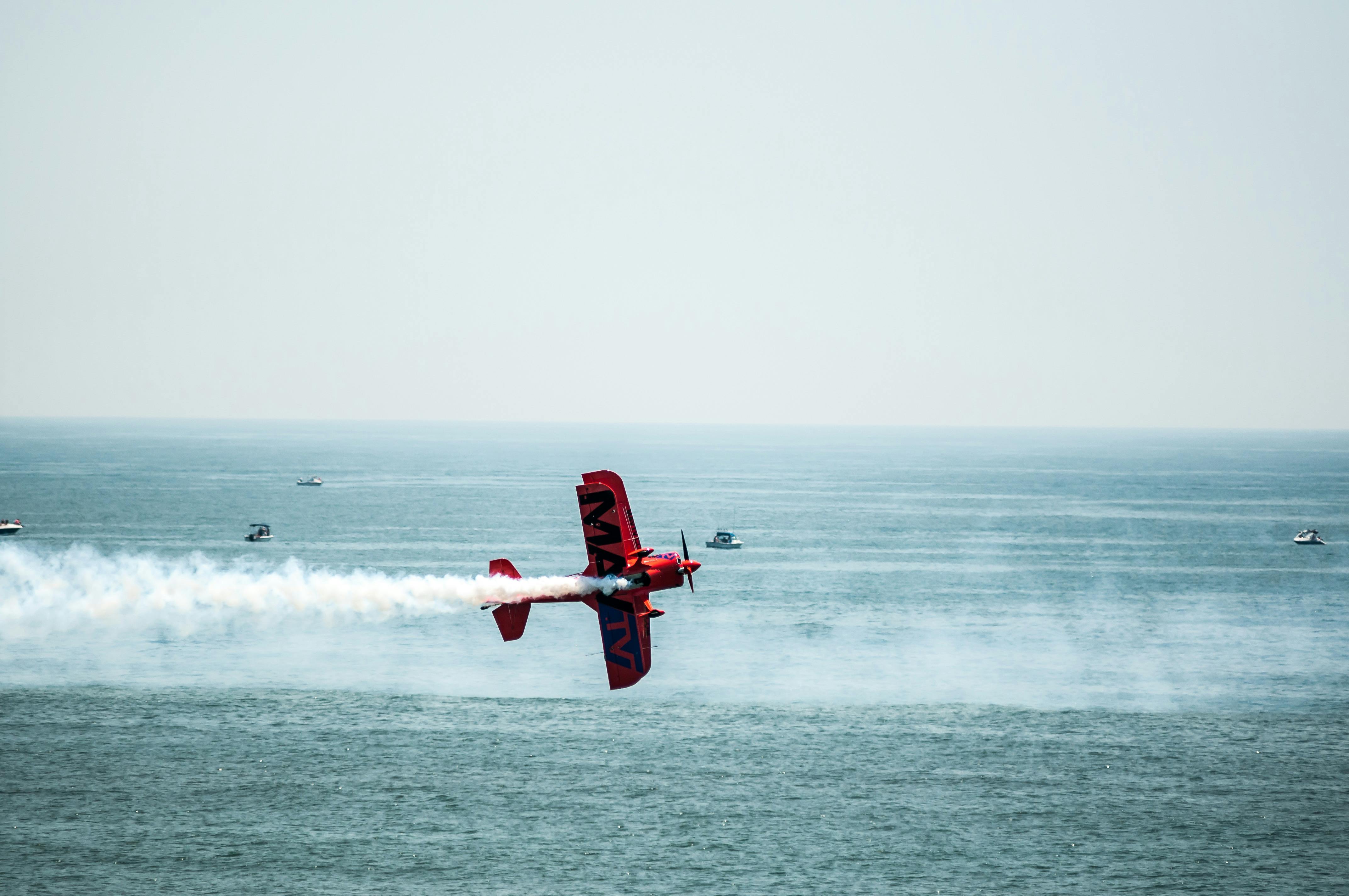 daring red biplane aerobatics over ocean waters