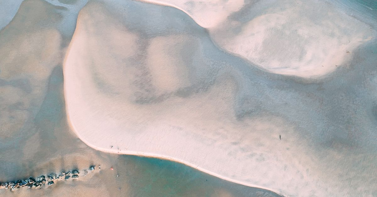 Aerial view of sandy shores with ocean patterns, creating a serene coastal landscape.