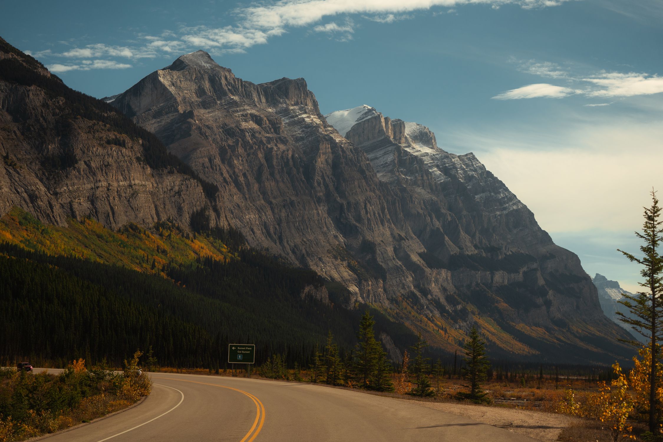 A winding road through a majestic mountain landscape during autumn.
