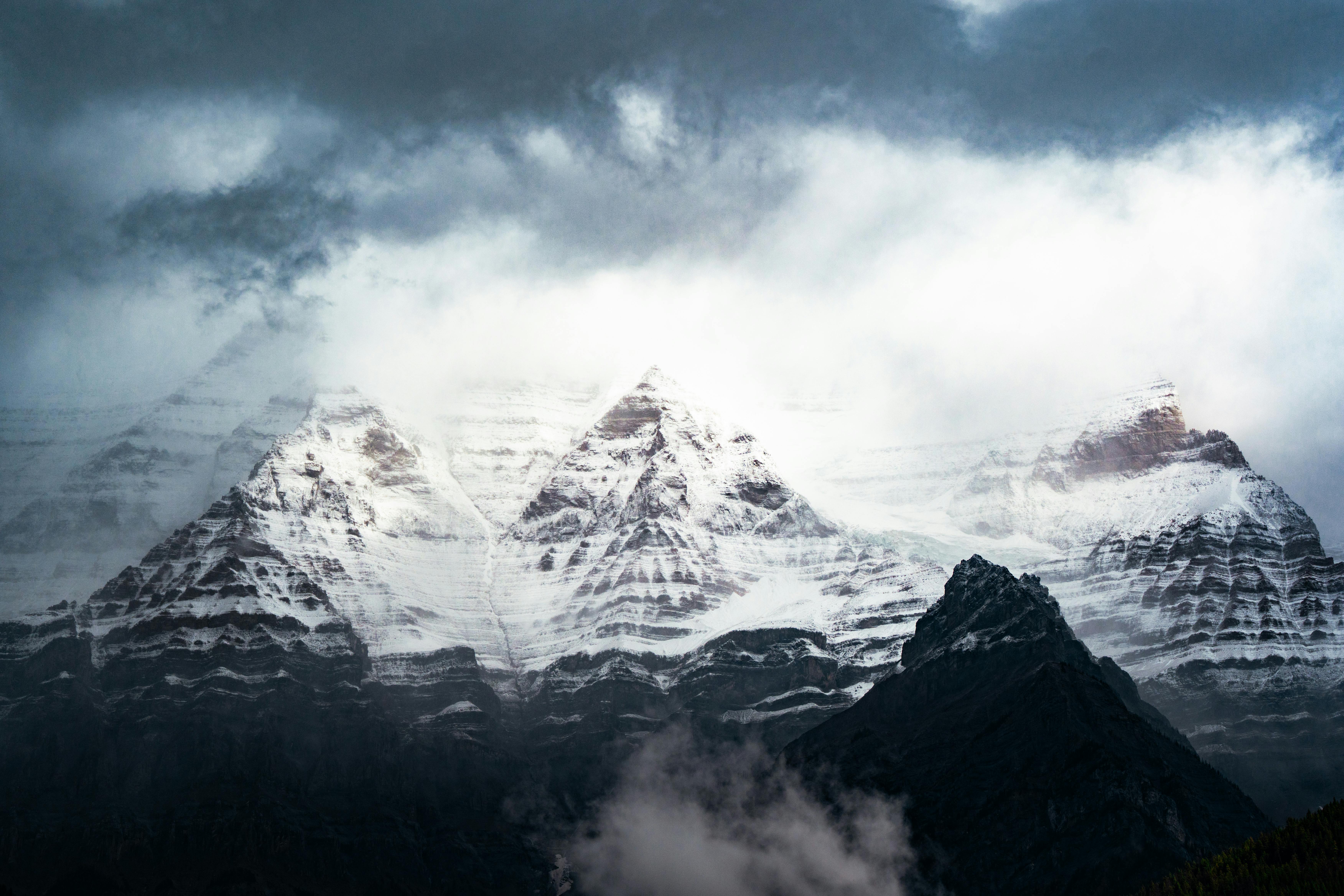 Stunning mountain peaks enveloped in snow and clouds during a dramatic day.