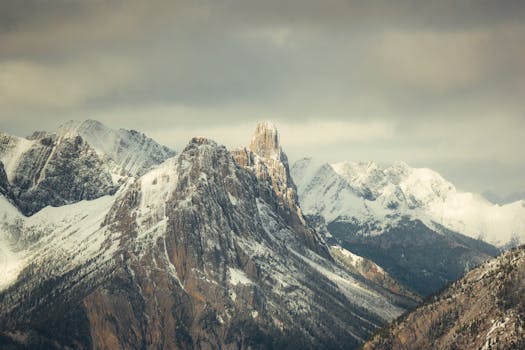 Majestic snow-capped mountains under cloudy skies, showcasing natural grandeur in winter.