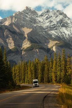 A scenic road winding through a forest with a majestic mountain in the background.