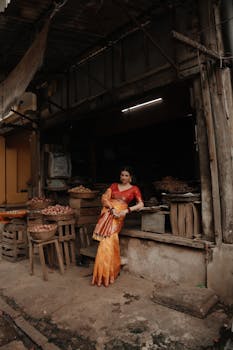 Woman in traditional attire standing in a rustic market environment.
