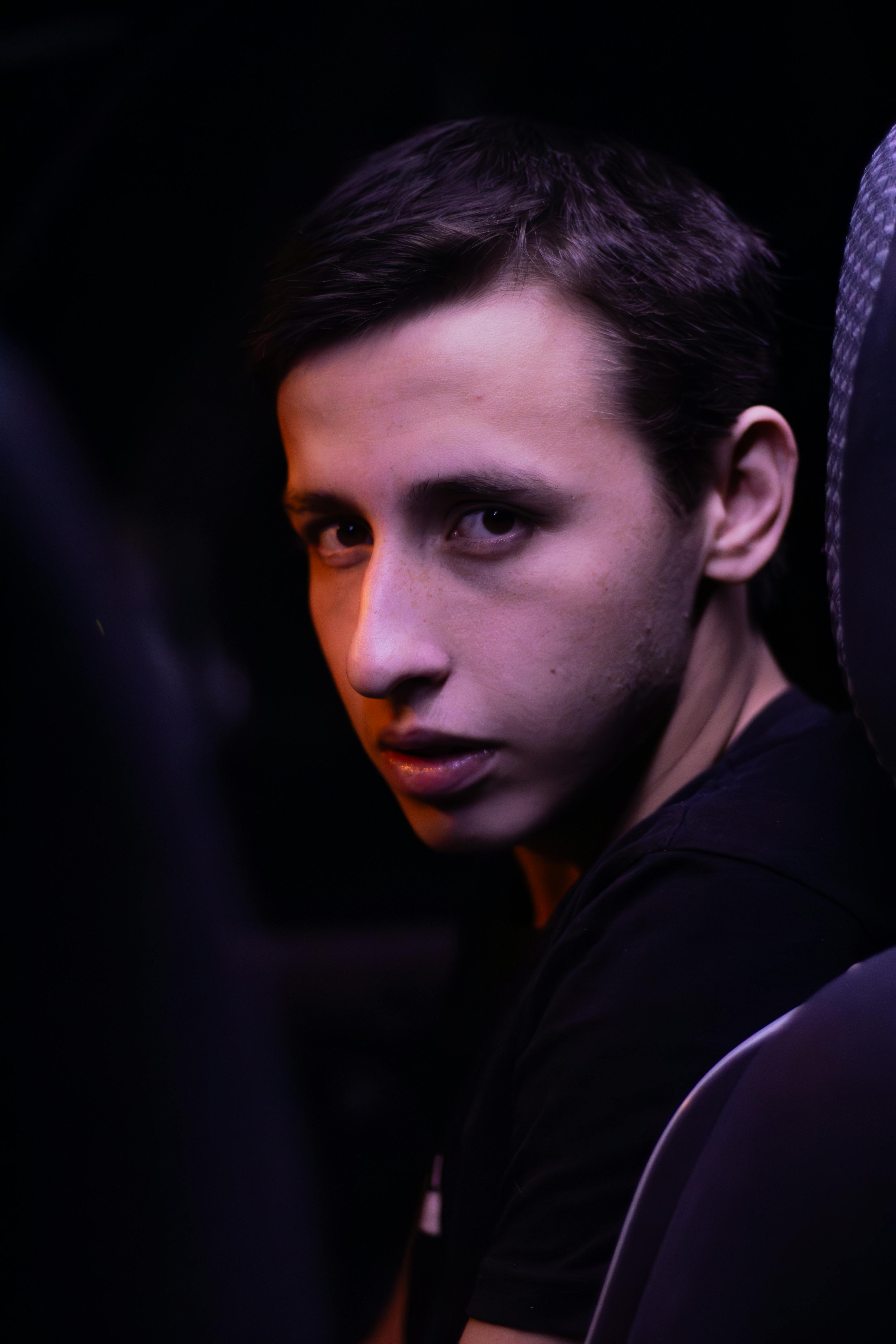 Dramatic portrait of a young man inside a car, illuminated by moody lighting.