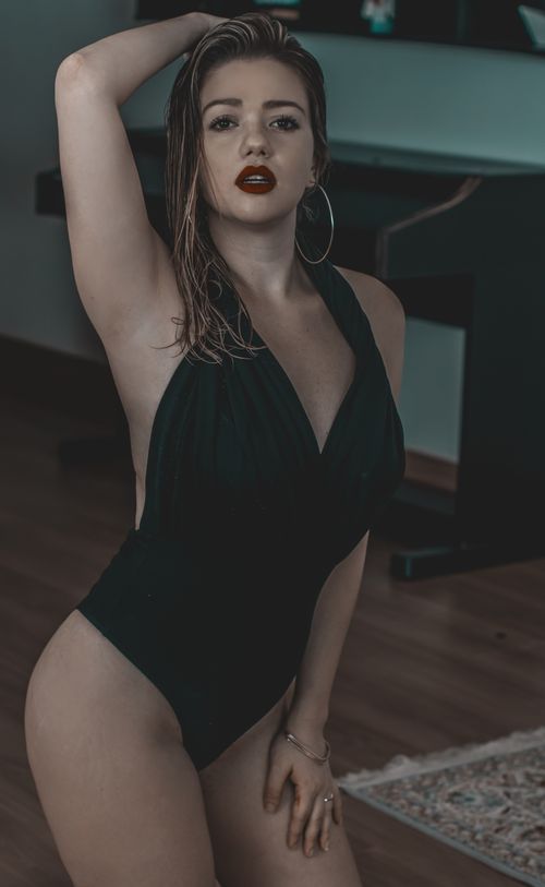 Free Elegant woman in a black swimsuit posing indoors with a seductive expression, embracing fashion and style. Stock Photo