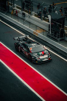 A sleek sports car in a pit lane, ready for a thrilling race on a cloudy day.