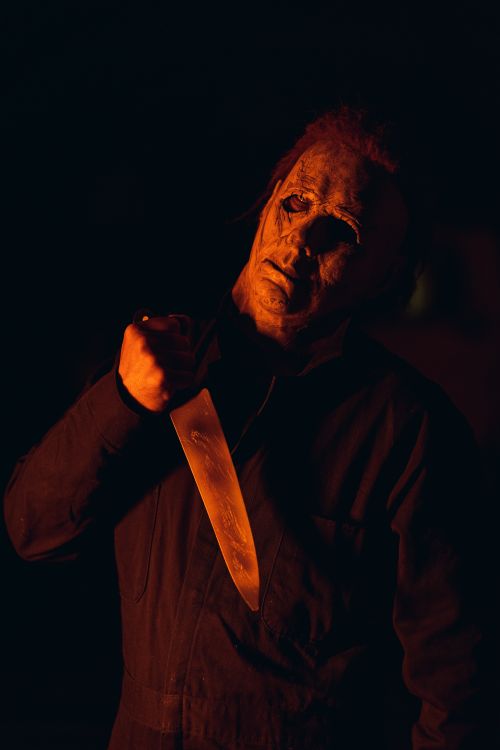 Free Intense scene featuring a masked figure gripping a knife, set against a dark background. Stock Photo