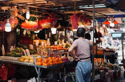 A busy street market scene with a variety of fresh fruits and attentive shopper.