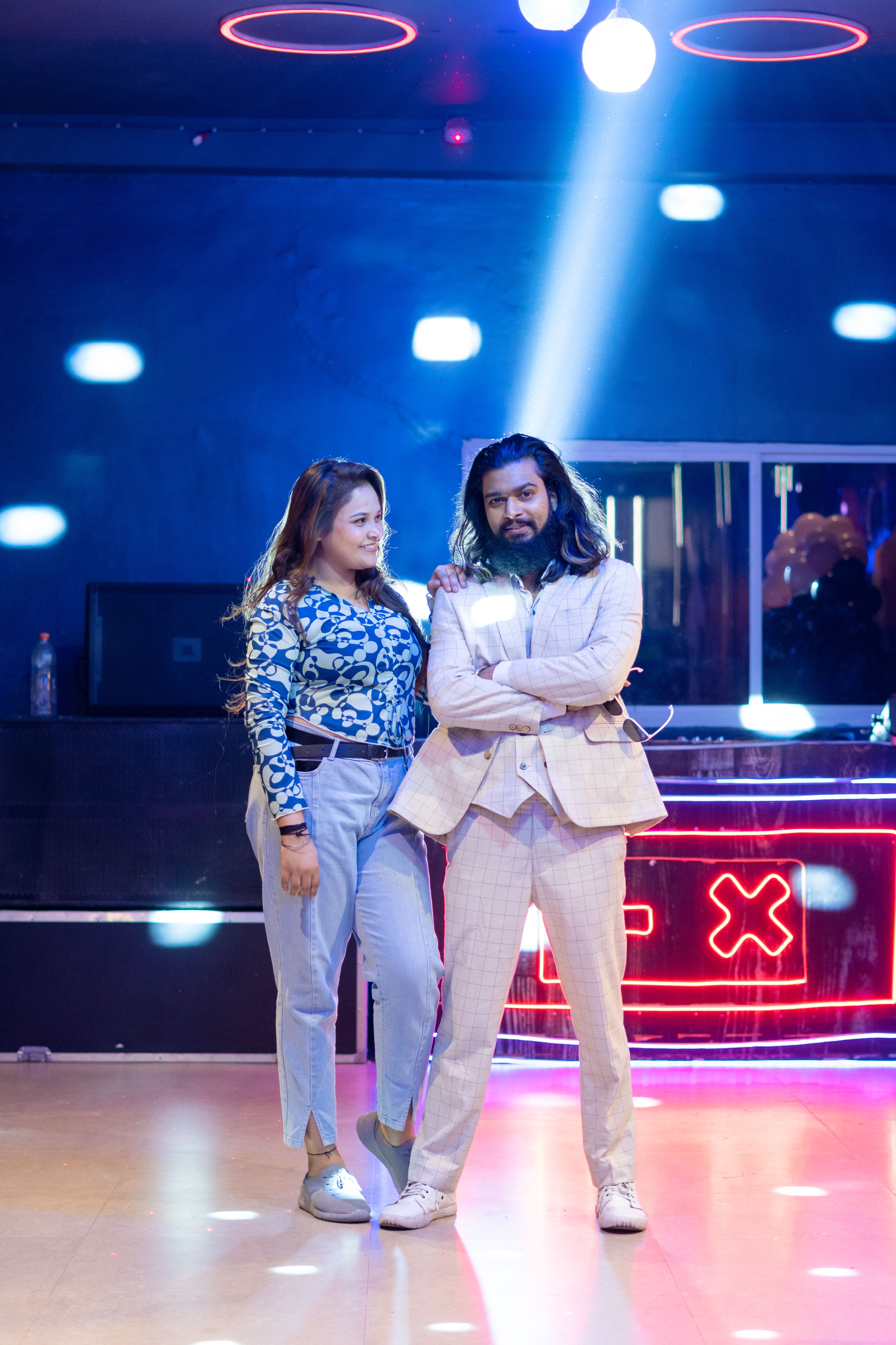 Stylish couple in a nightclub under vibrant lights, showcasing nightlife fashion.