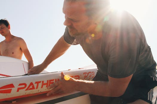 在明亮的阳光下，两名男子正为冲浪板做着准备，捕捉着完美的海滩时刻