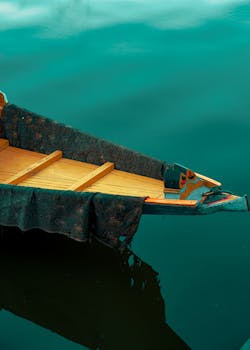 A serene image of a traditional Shikara boat resting on the calm waters of Dal Lake, Srinagar.