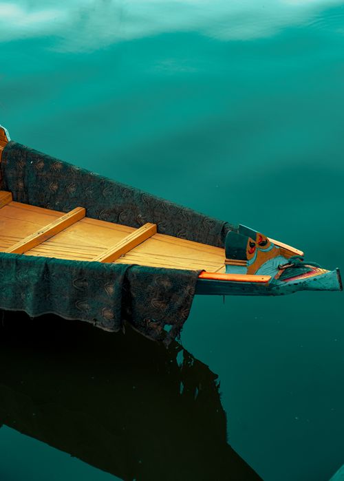 Free A serene image of a traditional Shikara boat resting on the calm waters of Dal Lake, Srinagar. Stock Photo