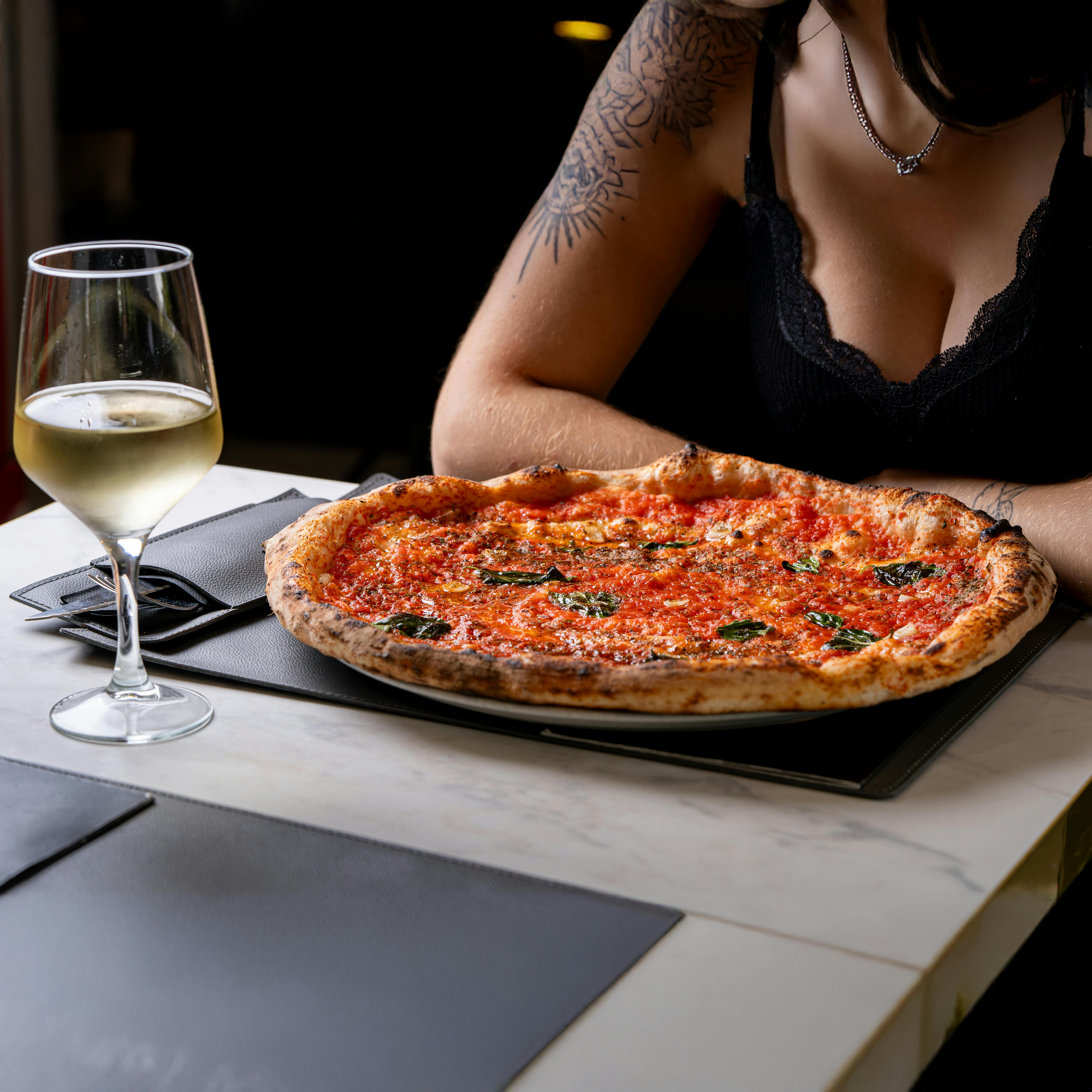 A sophisticated dining setup featuring a classic margherita pizza and a glass of white wine