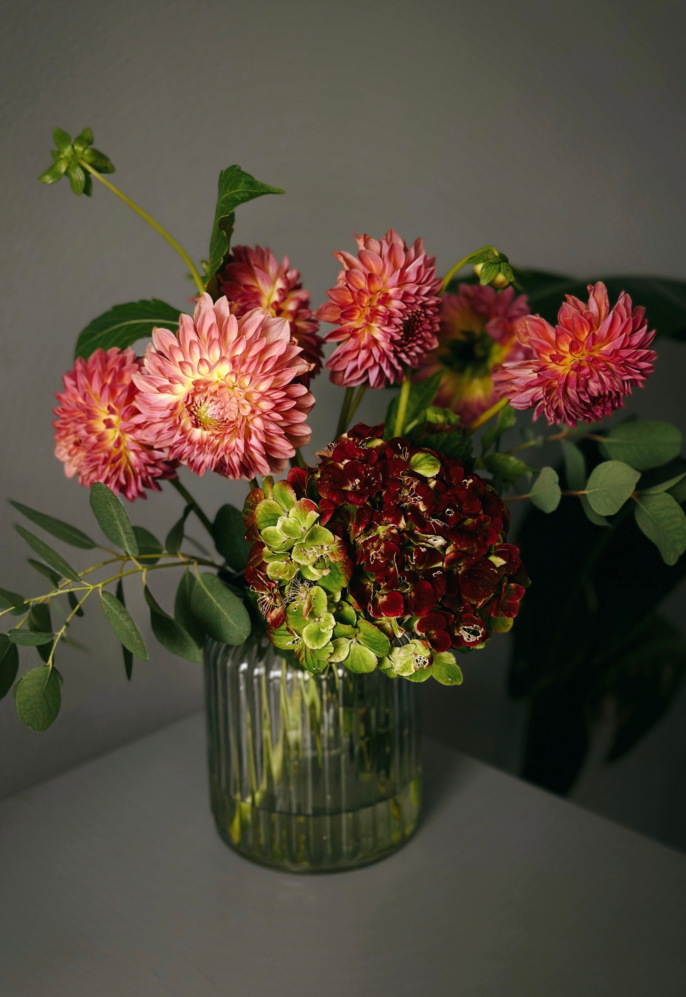 A beautiful floral arrangement with dahlias and hydrangeas in a glass vase.