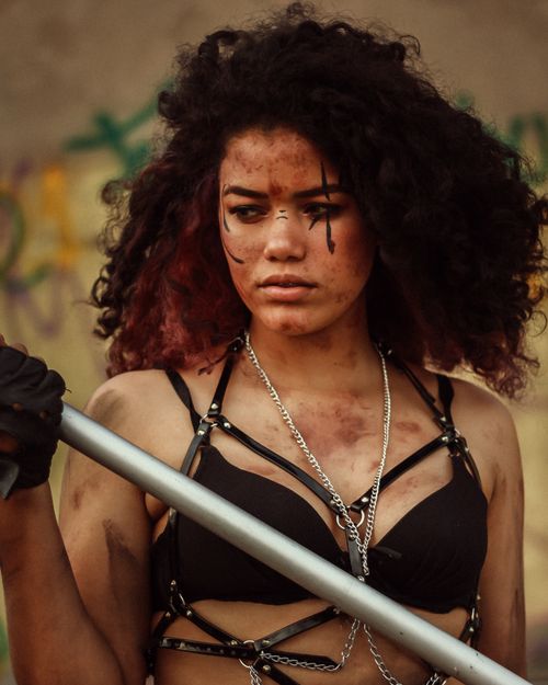 Free A young woman posing fiercely with war paint and grunge clothing, creating an intense post-apocalyptic style. Stock Photo