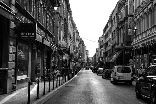Free Black and white view of a classic European street with vintage buildings and parked cars. Stock Photo