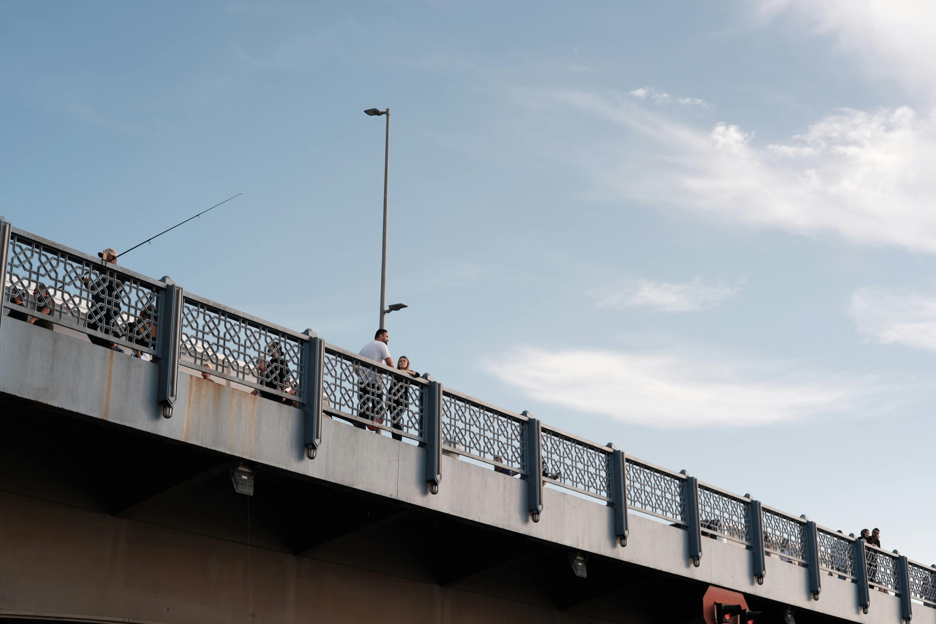 people fishing on bridge under clear sky