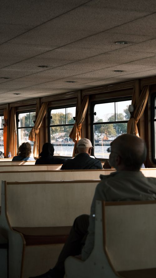 Free Passengers enjoy a calm ferry ride with scenic river views and cozy seating. Stock Photo