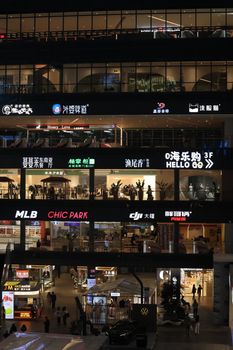 Urban shopping center illuminated with bright signs and bustling activity.