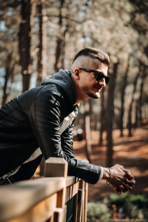 Free Young man in sunglasses enjoying a sunny day in a forest setting. Stock Photo