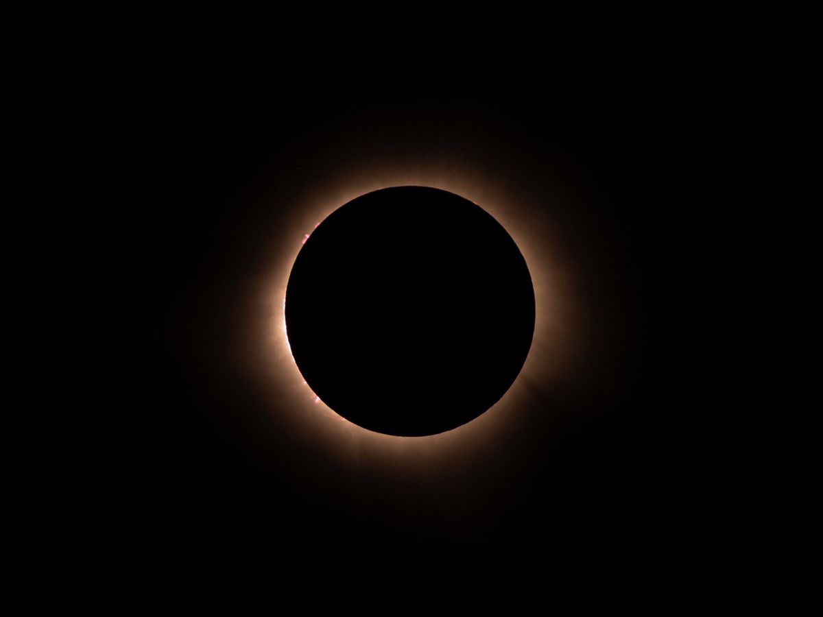Totale Sonnenfinsternis mit leuchtender Korona am dunklen Himmel