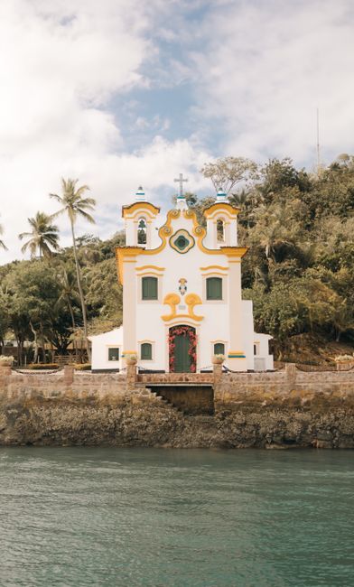 Beautiful colonial-style church set against lush greenery by the river.