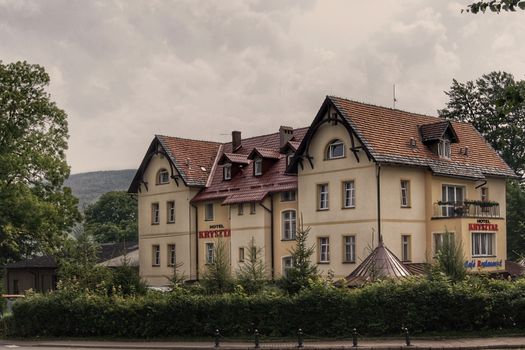 Elegant hotel in Świeradów-Zdrój, Poland with classic architecture amidst lush greenery.