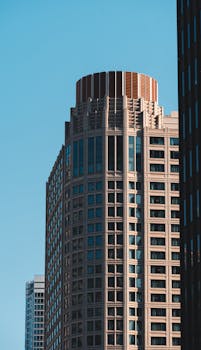 A modern skyscraper against a clear blue sky in an urban setting.