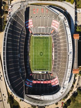 Stunning aerial view of a deserted football stadium with green field and tiered seats.