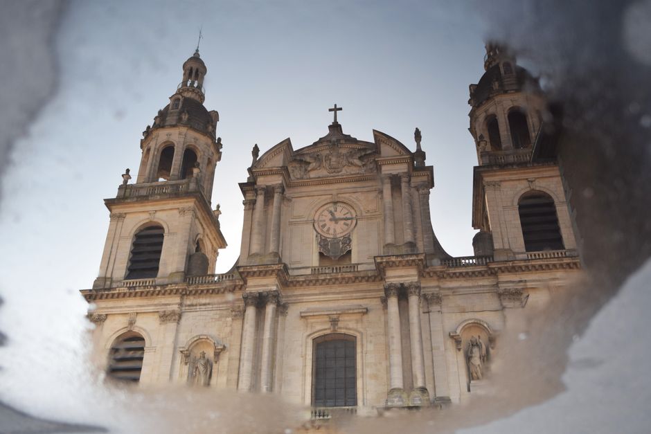 Reflection of a historic cathedral in a puddle, showcasing architecture.