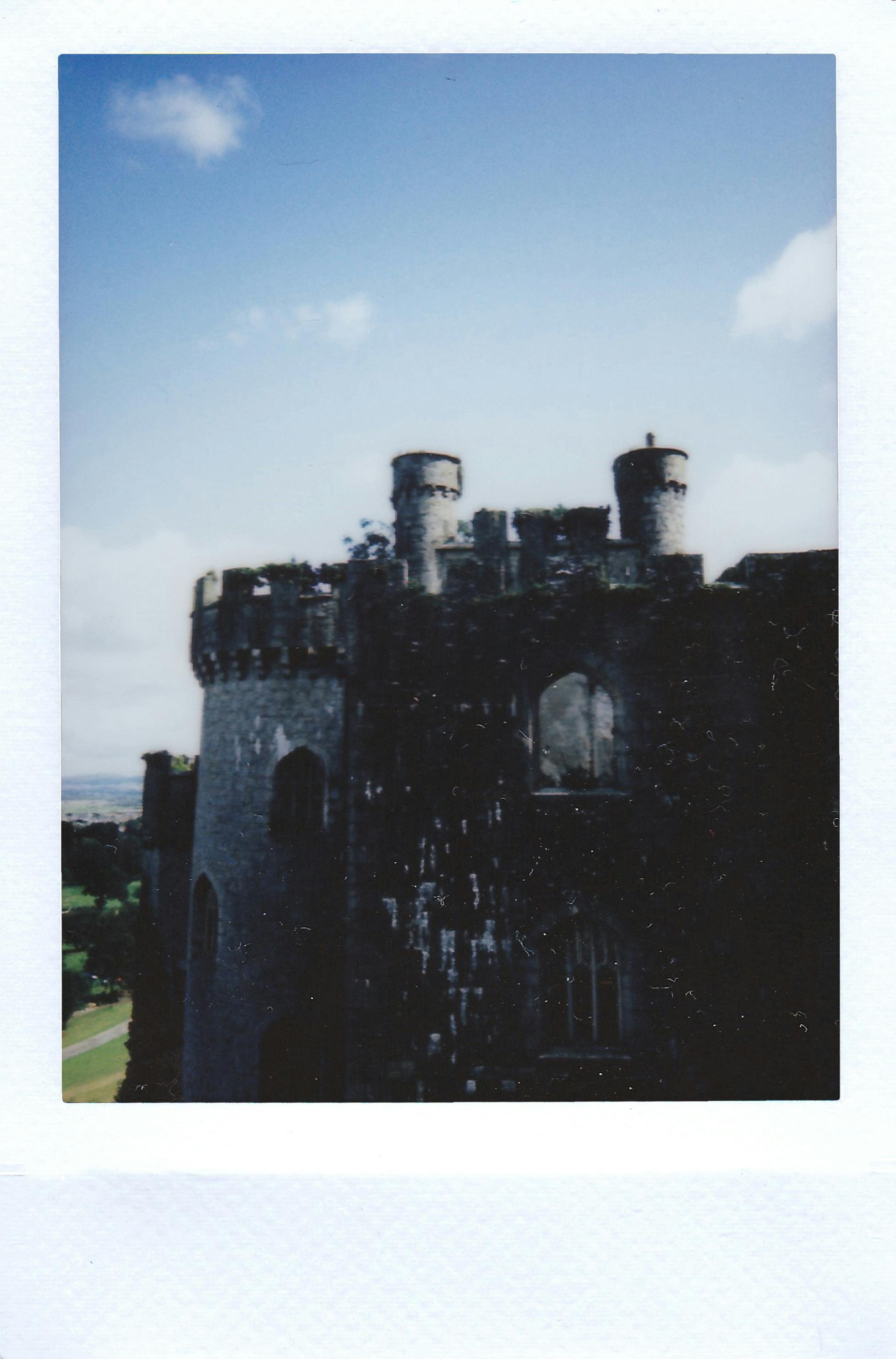A nostalgic polaroid capturing an ancient castle's exterior under a blue sky.