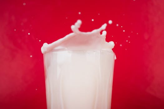 Dramatic splash of milk captured against a vibrant red background.
