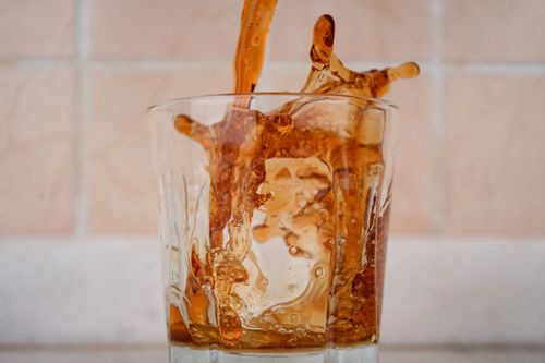 Free Close-up of a brown liquid splash captured in motion inside a clear glass. Stock Photo