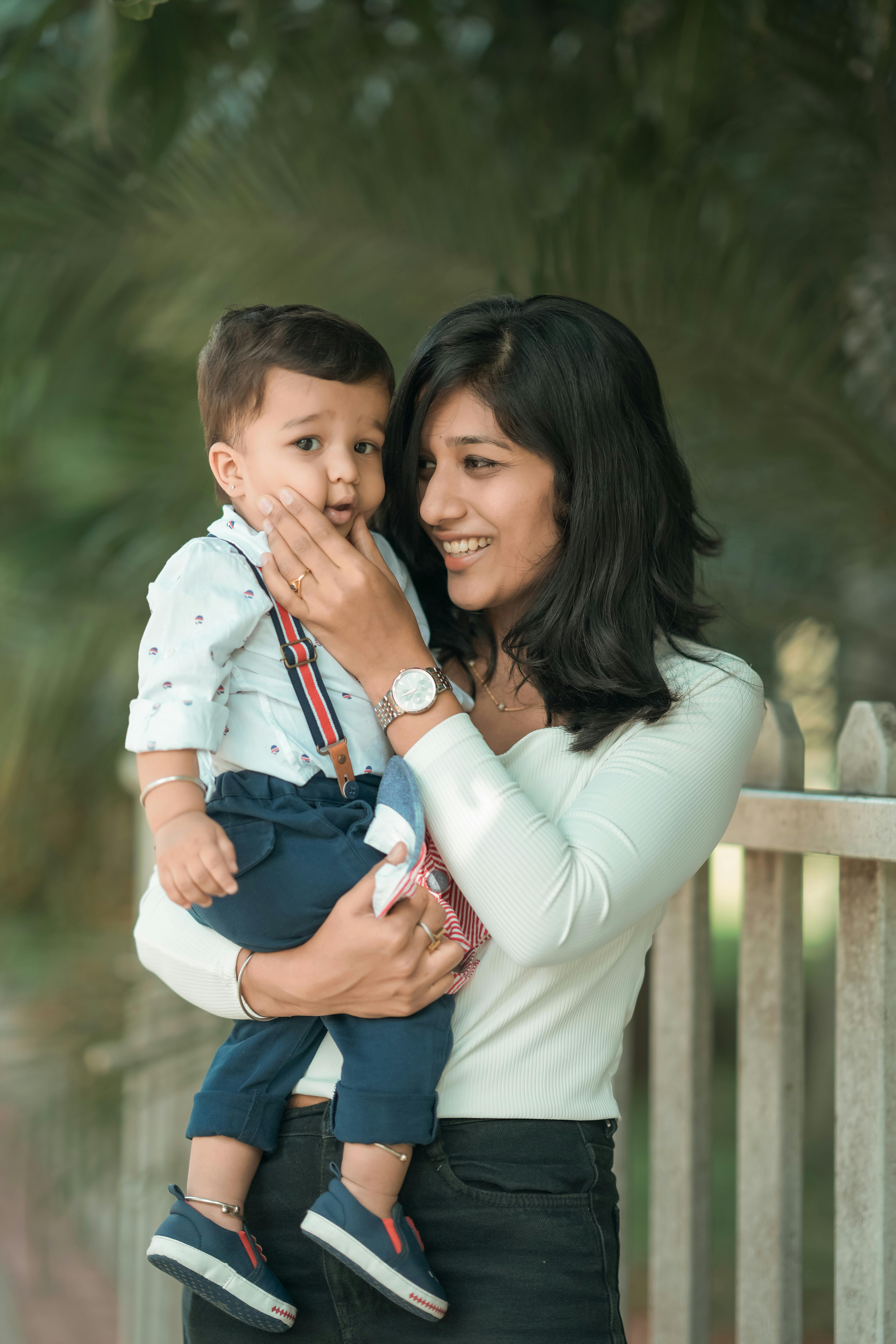Happy mother holding her young son, standing outdoors with a warm smile.