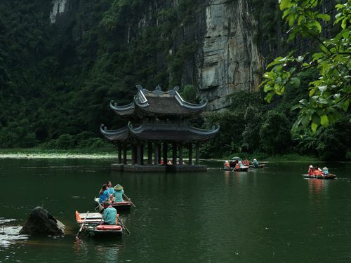 Free Traditional boats navigate the serene waters of Ninh Bình with lush karst landscape backdrop. Stock Photo