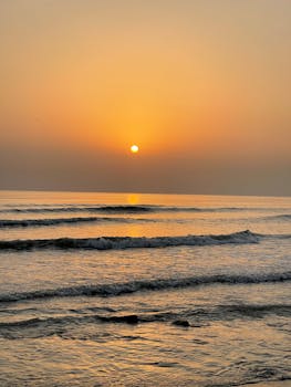 Calm sunrise over the ocean with gentle waves and a soft horizon.