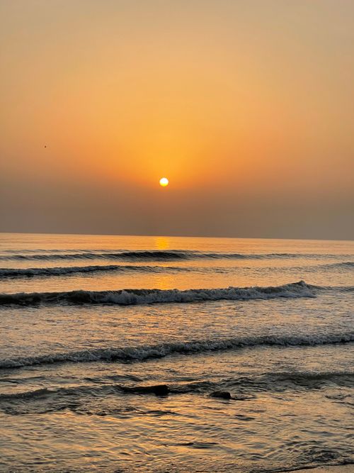Free Calm sunrise over the ocean with gentle waves and a soft horizon. Stock Photo