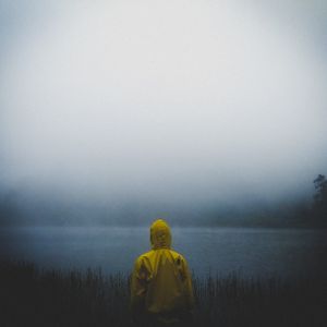 A figure in a yellow raincoat by a misty lake — photo by Gagaz Adam on Pexels