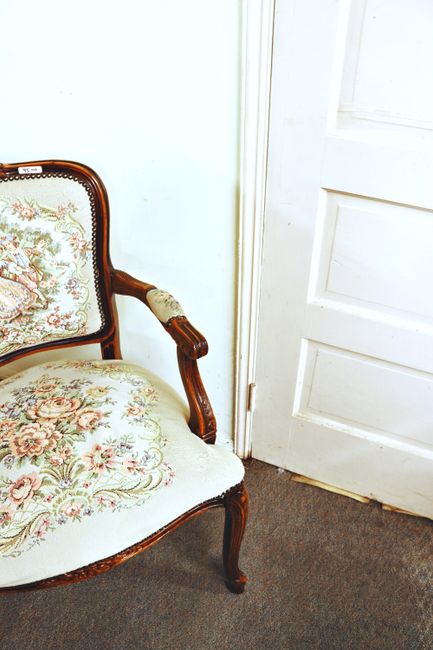 Elegant vintage floral armchair in home interior with wooden details and soft upholstery.