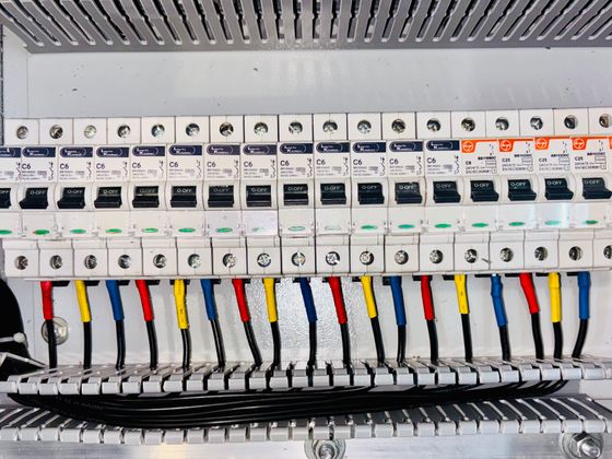 An open circuit breaker panel with colour-coded wiring