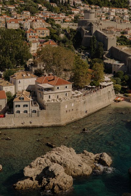 Scenic aerial view of Dubrovnik's historic coastline with ancient walls and clear waters.