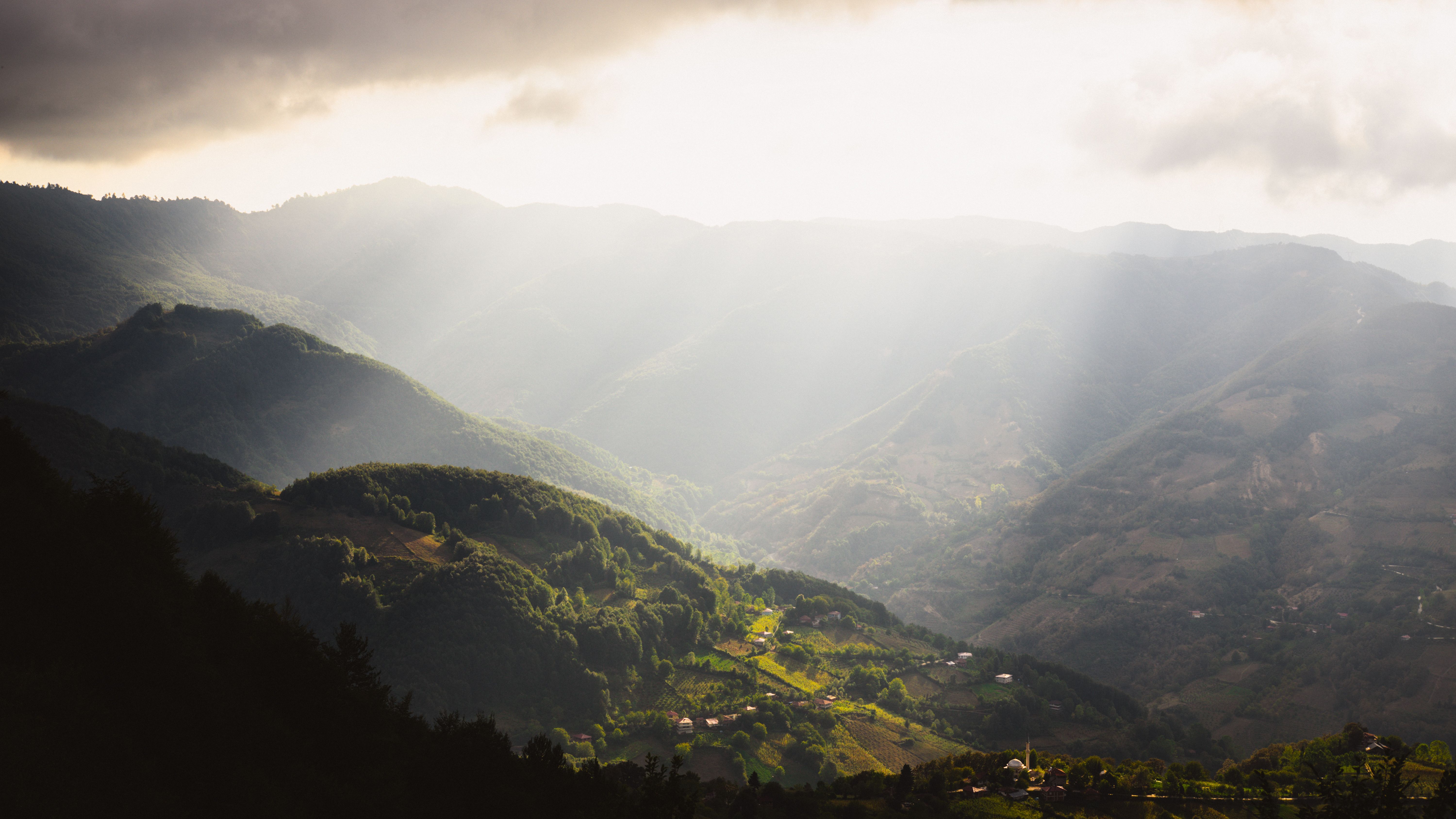 Breathtaking view of sunlit mountains in Erbaa, Türkiye under dramatic skies.