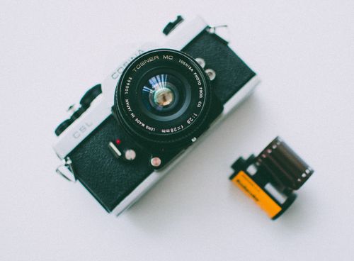 Free Close-up of a classic film camera and roll on a white background, showcasing vintage photography equipment. Stock Photo