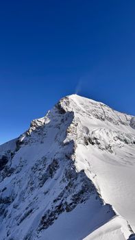 Stunning view of snow-capped peaks in Lauterbrunnen, Switzerland under a clear blue sky.