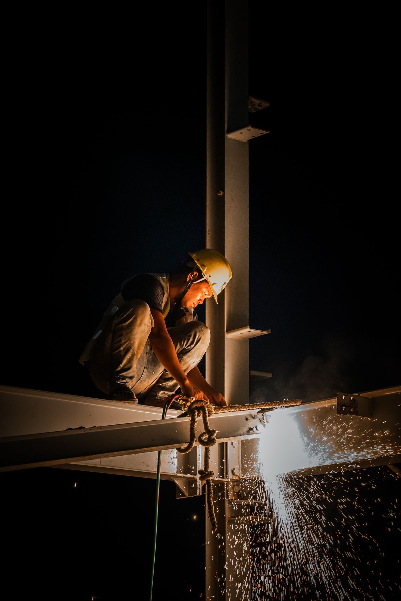 Structural welding continuing at night under the beams