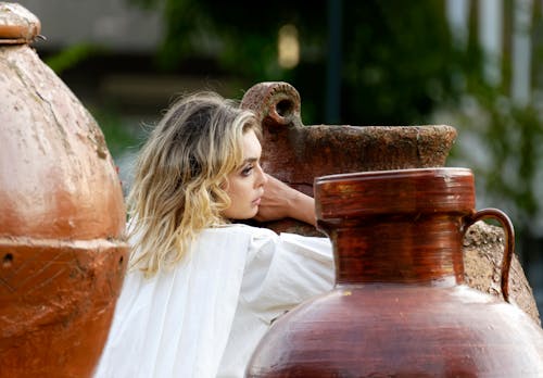 Selective Focus Photo of Woman Leaning on Huge Jar