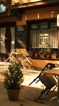 A charming outdoor cafe with inviting chairs and warm lighting during day time.