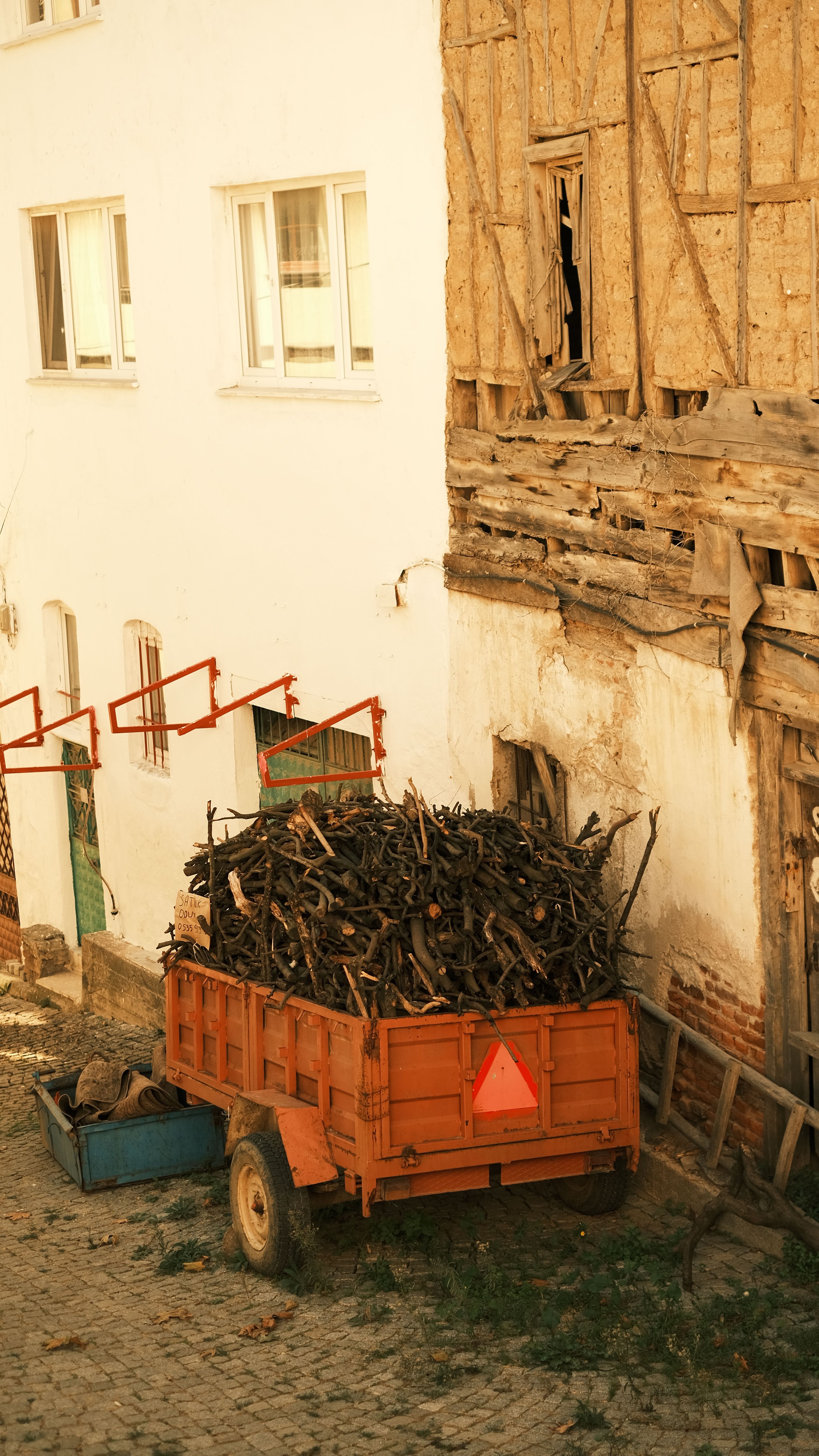 Rustic wooden cart filled with firewood against a vintage building facade in a quaint alley.