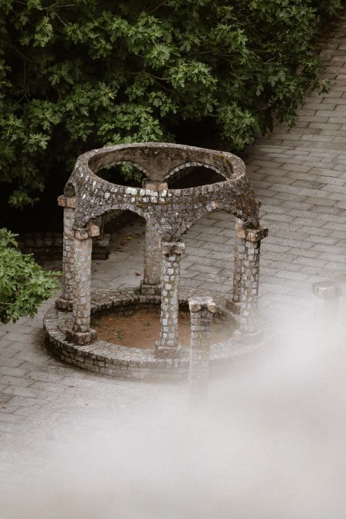 Free Elevated view of a weathered stone gazebo surrounded by greenery in a garden. Stock Photo